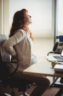 Беременная деловая женщина сдерживает себя, сидя на кресле в офисе — стоковое фото