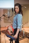 Femme ajustant le volume tout en chantant en studio de musique — Photo de stock