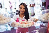 Портрет продавщицы, держащей поднос с турецкими сладостями у прилавка в магазине — стоковое фото