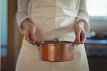 Partie médiane de la femme tenant le pot dans la cuisine à la maison — Photo de stock