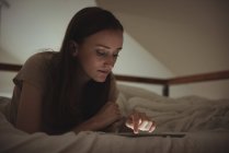 Frau nutzt digitales Tablet zu Hause im Bett — Stockfoto