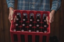 Primer plano del hombre que lleva botellas de cerveza caseras en una caja - foto de stock