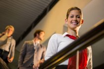 Portrait of smiling female staff standing on escalator in airport — Stock Photo