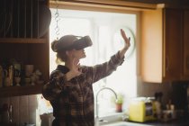 Женщина испытывает виртуальную реальность гарнитура на кухне дома — стоковое фото