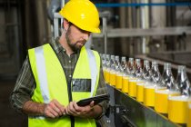 Serious male worker using digital tablet in juice factory — Stock Photo