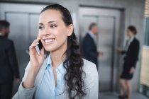 Businesswoman talking on mobile phone in office — Stock Photo