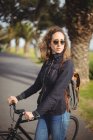 Femme debout avec vélo sur la route — Photo de stock