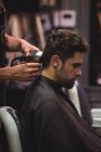 Чоловік отримує волосся, обрізане перукарем з тримером у перукарні — стокове фото