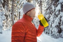 L'uomo che beve acqua dalla bottiglia nella foresta durante l'inverno — Foto stock