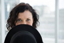 Porträt einer Tänzerin, die ihr Gesicht mit Hut im Studio versteckt — Stockfoto