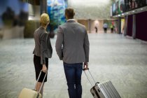 Rear view of business people with luggage at airport terminal — Stock Photo
