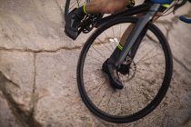 Low section of athlete riding bicycle on cracked road — Stock Photo