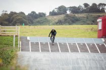Cyclist riding BMX bike on starting ramp at skatepark — Stock Photo