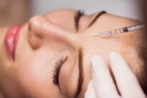 Paciente femenina joven que recibe inyección cosmética en la cara en clínica estética - foto de stock