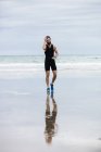 Schöner Athlet joggt am Strand — Stockfoto