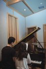 Vista trasera de una pareja tocando un piano en un estudio de grabación - foto de stock