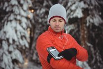 Человек слушает музыку на мобильном телефоне зимой — стоковое фото