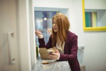 Junge Frau benutzt Handy beim Salatessen — Stockfoto