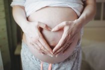 Mittlere Sektion der Schwangeren berührt ihren Bauch im Schlafzimmer zu Hause — Stockfoto