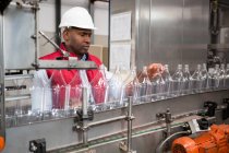 Confident male employee examining bottles in juice factory — Stock Photo