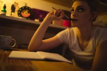 Frau denkt beim Schreiben von Notizen im Salon zu Hause — Stockfoto