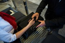 Mid section of female staff handing over luggage to businessman — Stock Photo