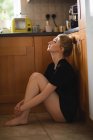 Femme réfléchie assise dans la cuisine à la maison — Photo de stock