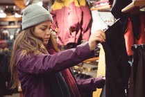 Femme sélectionnant des vêtements dans un magasin de vêtements — Photo de stock