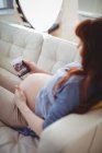 Donna incinta che si rilassa sul divano e guarda la sonografia in soggiorno — Foto stock