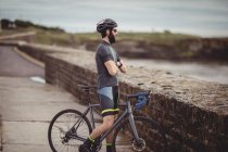 Sportler steht mit Fahrrad auf Küstenstraße — Stockfoto