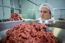 Butcher putting meat in mincer machine at meat factory — Stock Photo