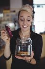 Retrato de garçonete segurando jarra de biscoitos no balcão no café — Fotografia de Stock