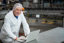 Porträt eines glücklichen männlichen Arbeiters mit Laptop in der Fabrik — Stockfoto