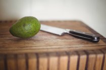 Крупный план авокадо и ножа на деревянном столе — стоковое фото