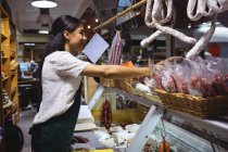 Personal femenino que trabaja en el mostrador de carne en el supermercado - foto de stock