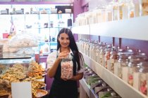 Portrait de femme commerçante tenant un pot de bonbons turcs au comptoir dans un magasin — Photo de stock