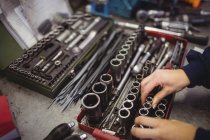 Mains de mécanicienne organisant divers outils dans le garage de réparation — Photo de stock
