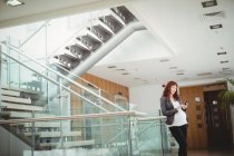 Schwangere Geschäftsfrau benutzt Handy in der Nähe von Treppe im Büro — Stockfoto