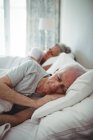 Старшая пара спит на кровати в спальне — стоковое фото
