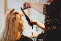 Close-up of female hairdresser styling clients hair in saloon — Stock Photo