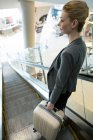 Geschäftsfrau mit Gepäck fährt auf Rolltreppe am Flughafen-Terminal nach unten — Stockfoto
