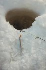 Caña de pescar alrededor del agujero de hielo en nieve - foto de stock
