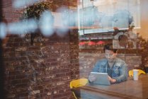Человек с цифровой планшет с чашкой кофе на столе в кафе — стоковое фото
