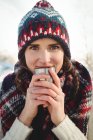 Красива жінка в зимовому одязі випиває чашку під час лижних канікул — стокове фото