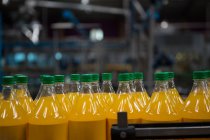 Close up of yellow juice bottles in factory — Stock Photo