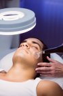 Мужчина получает массаж лица для косметического лечения в клинике — стоковое фото