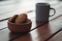 Close-up of biscuits in bowl on desk with coffee cup — Stock Photo