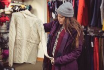 Женщина выбирает одежду в магазине одежды — стоковое фото