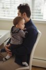 Father holding his baby while sitting at desk — Stock Photo