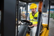 Young male worker sitting in forklift at warehouse — Stock Photo